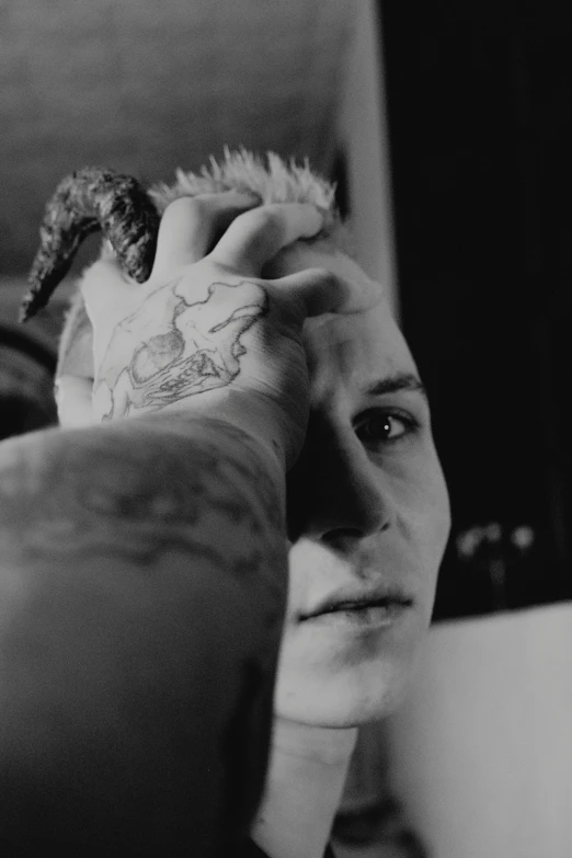 a black and white photo of a man with a tattoo on his arm, a tattoo, inspired by Seb McKinnon, vergil from devil may cry, his hands buried in his face, lizard head, reflection