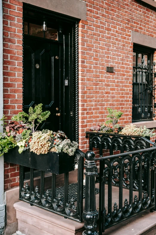 a black iron fence in front of a red brick building, planters, julia sarda, residential, tall entry