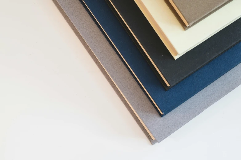 a stack of books stacked on top of each other, a minimalist painting, unsplash, bauhaus, light grey blue and golden, panel of black, birdseye view, wood and paper