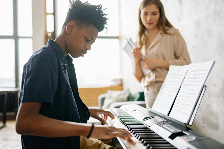 a boy is playing the piano while a woman looks on, trending on pexels, american barbizon school, black teenage boy, australian, no watermarks, thumbnail