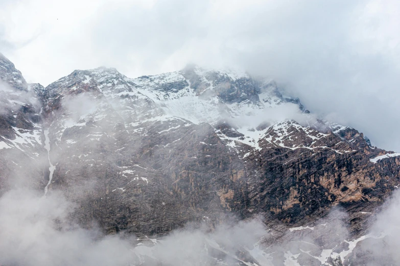 a group of people standing on top of a snow covered mountain, pexels contest winner, low clouds after rain, “ aerial view of a mountain, rocky cliff, middle close up composition