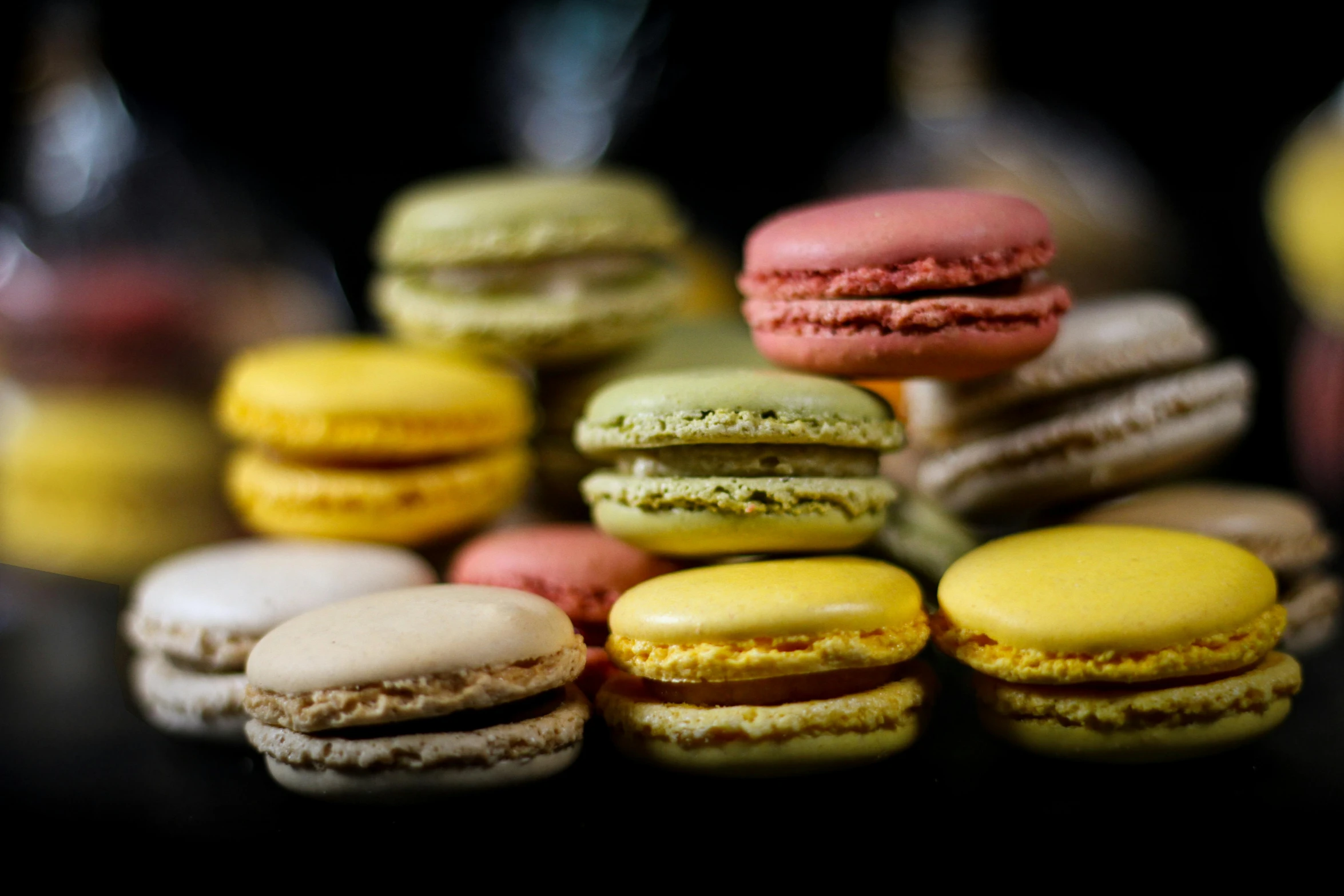 a pile of macarons sitting on top of a table, a portrait, by Sylvia Wishart, pexels, in front of a black background, made of food, thumbnail, coloured