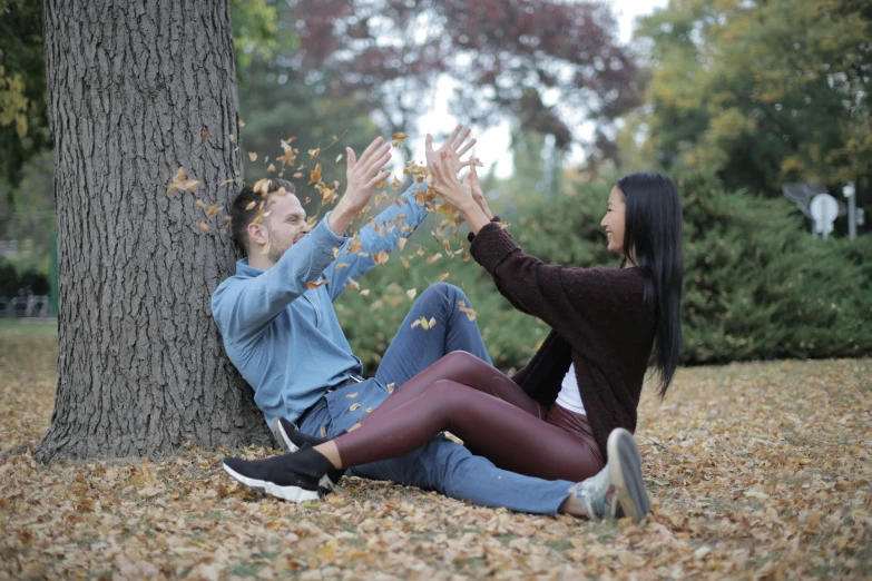 a man and a woman sitting next to a tree, falling leaves, avatar image, shot on 1 5 0 mm, waving