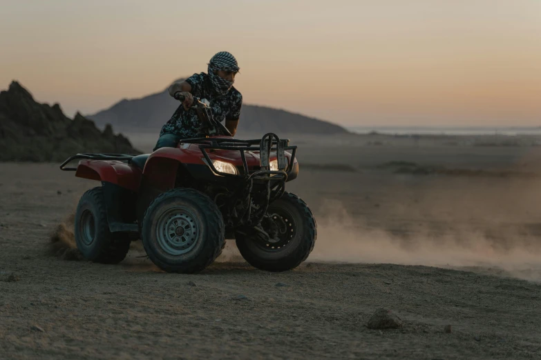 a man riding on the back of a red four wheeler, unsplash, hollister ranch, evening time, profile image, action sports