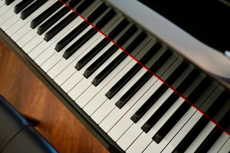 a close up of a piano keyboard on a table, lit from above, with accurate features, portrait n - 9, black steel with red trim