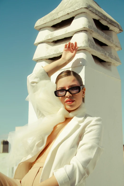 a woman sitting on top of a white tower, an album cover, inspired by Sergio Burzi, unsplash, bauhaus, wearing white suit and glasses, at a fashion shoot, in the sun, dasha taran
