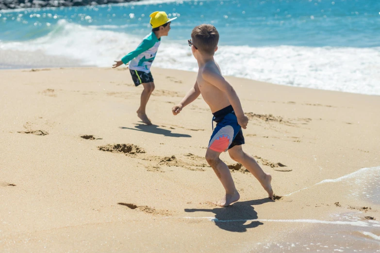 two young boys playing with a frisbee on the beach, by Thomas Furlong, pexels contest winner, happening, maui, footprints in the sand, on a hot australian day, 4 k quality