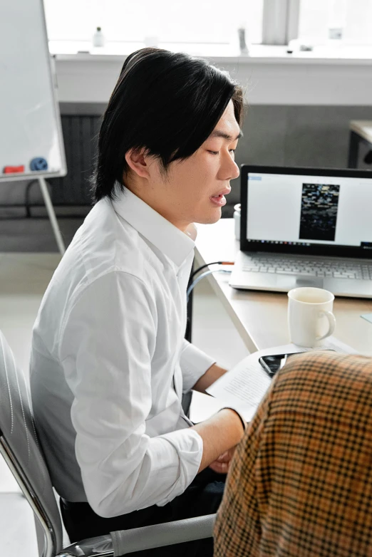 a man sitting at a desk in front of a laptop computer, inspired by Fei Danxu, designer product, studio kyoto, teaching, looking across the shoulder