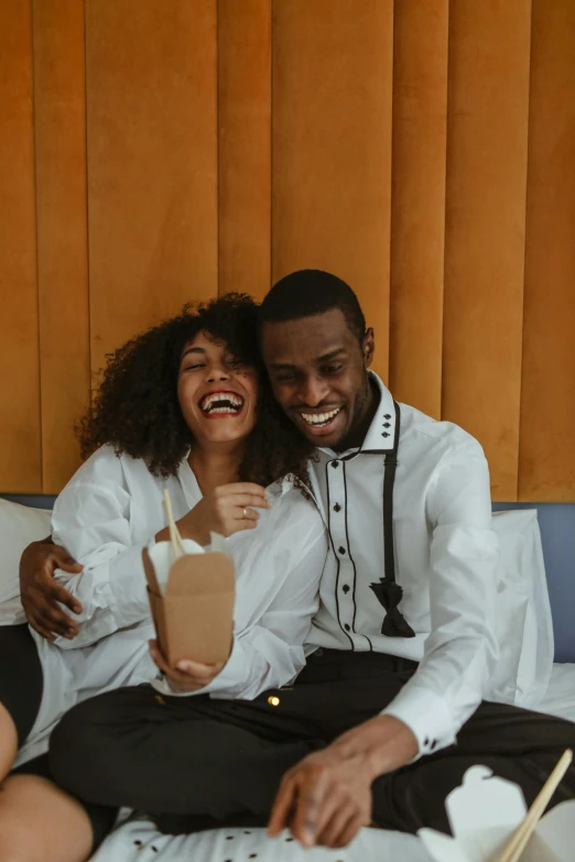 a man and a woman are sitting on a bed, by Adam Saks, pexels contest winner, earing a shirt laughing, holding a gold bag, ashteroth, fine dining