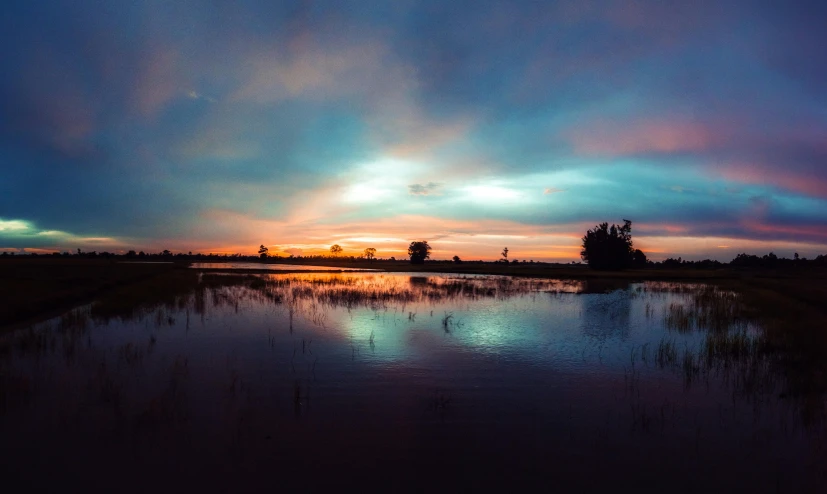 a large body of water with a sunset in the background, by Jan Tengnagel, unsplash, hurufiyya, floodplains, lake blue, multiple stories, colored photo