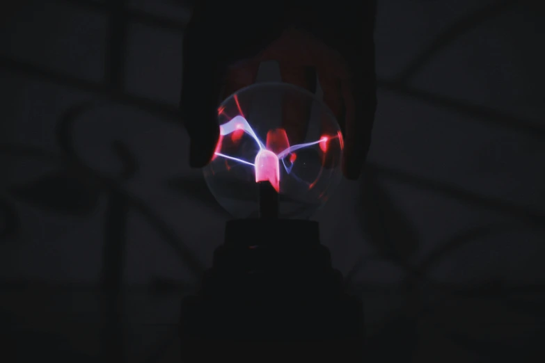 a person holding a light up in the dark, a hologram, inspired by Bruce Munro, unsplash, kinetic art, vecna from stranger things, plasma globe, detailed glowing red implants, magicavoxel cinematic lighting