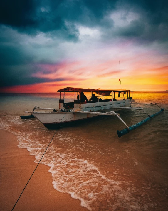 a boat sitting on top of a sandy beach, during a sunset