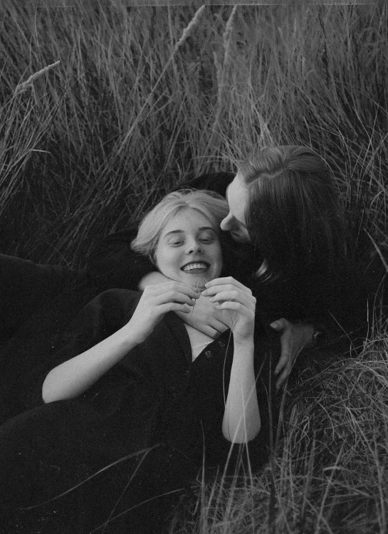 a black and white photo of two women laying in tall grass, tumblr, romanticism, 💣 💥💣 💥, man and woman in love, still from l'estate, happy cozy feelings