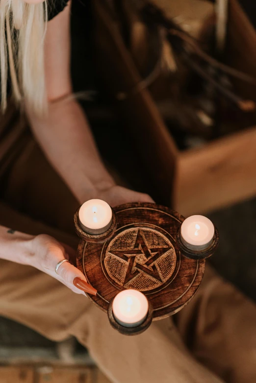 a woman holding a wiccah with candles in it, trending on pexels, geometric wood carvings, pentacle, the three fates, natural lights