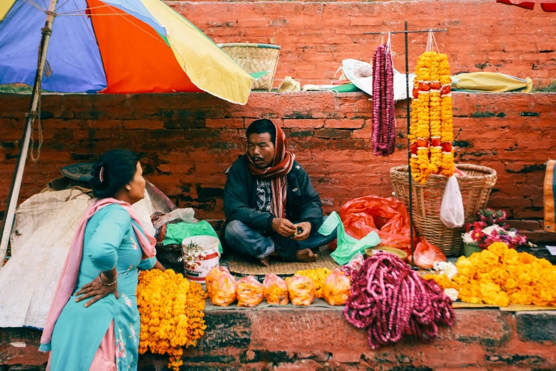 a man and a woman sitting under an umbrella, pexels contest winner, hurufiyya, colored market stand, nepal, clothes made out of flower, thumbnail