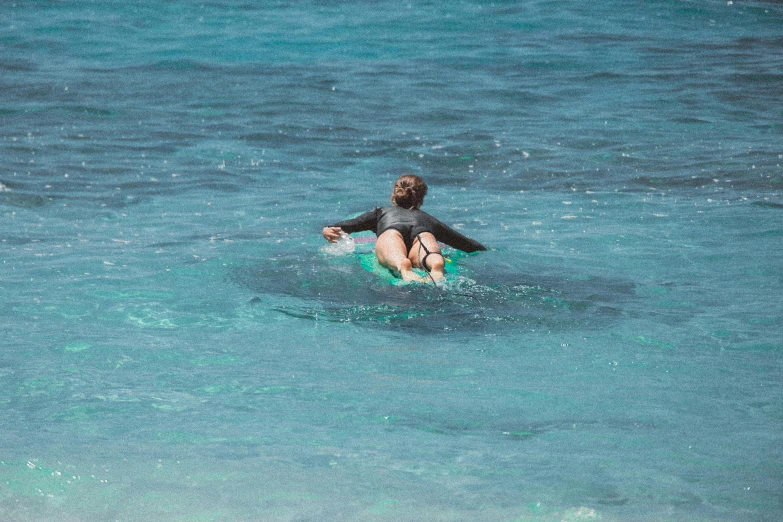 a person riding a surf board on a body of water, turquoise water, whealan, in the sun, female gigachad