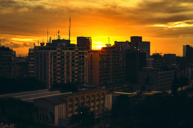 the sun is setting over the city skyline, by Lee Loughridge, pexels contest winner, jamaica, dramatic golden light, wide high angle view, stylized photo