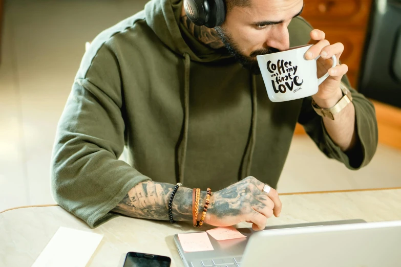 a man sitting at a table with a laptop and a cup of coffee, a tattoo, trending on pexels, arbeitsrat für kunst, wearing a headset, 9 9 designs, profile pic, thumbnail