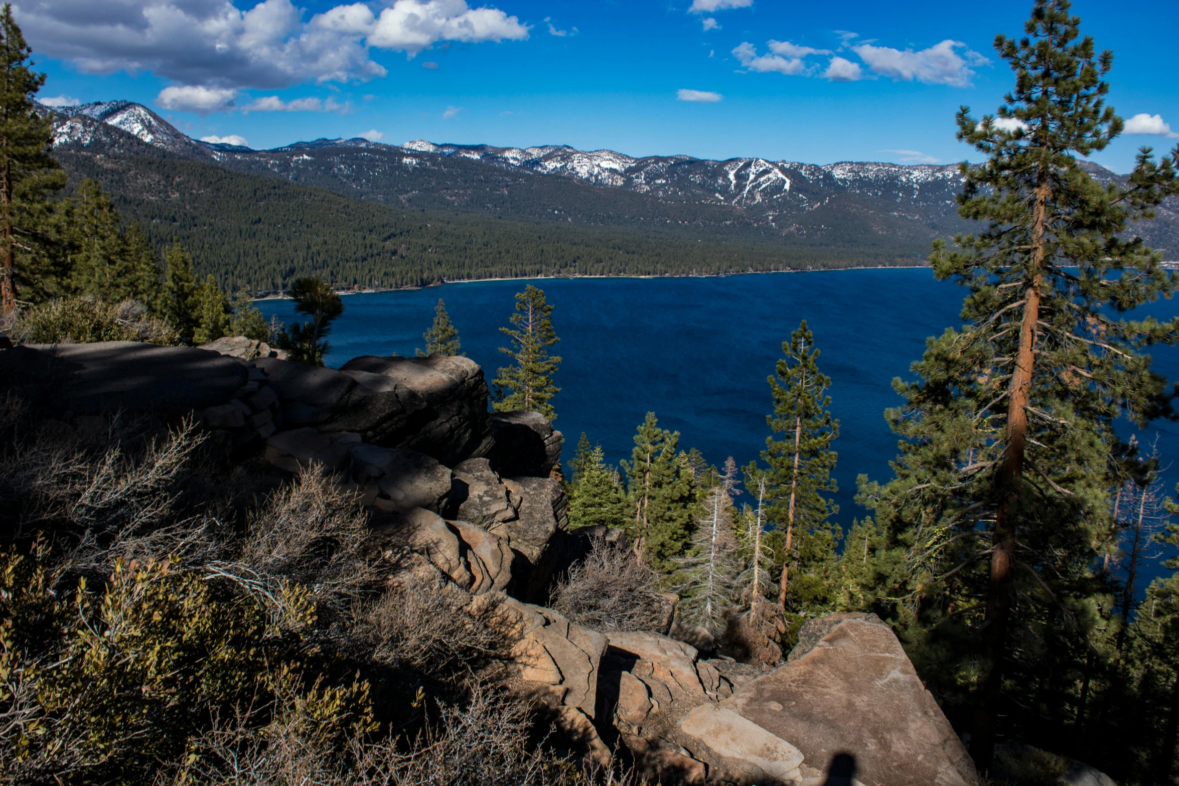 a large body of water surrounded by trees, a picture, by Meredith Dillman, unsplash, hurufiyya, big bear lake california, looking down a cliff, obsidian towers in the distance, slide show