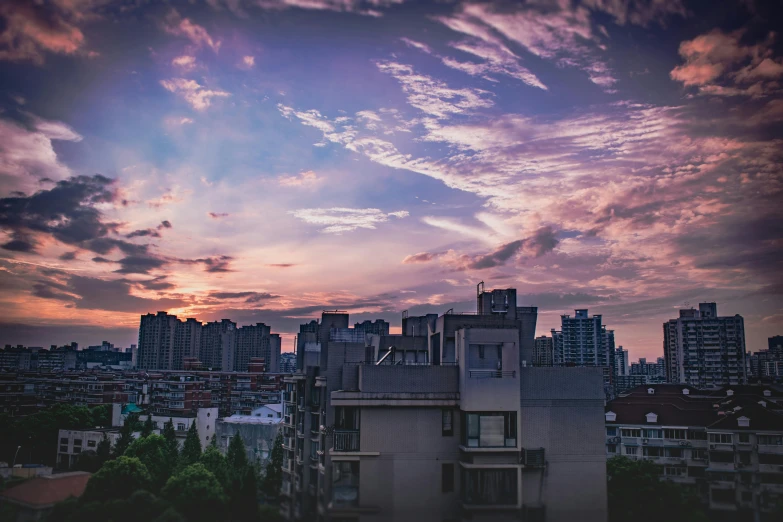 a very tall building sitting in the middle of a city, inspired by Elsa Bleda, pexels contest winner, dark purple clouds, guangjian, rooftop romantic, summer sunset