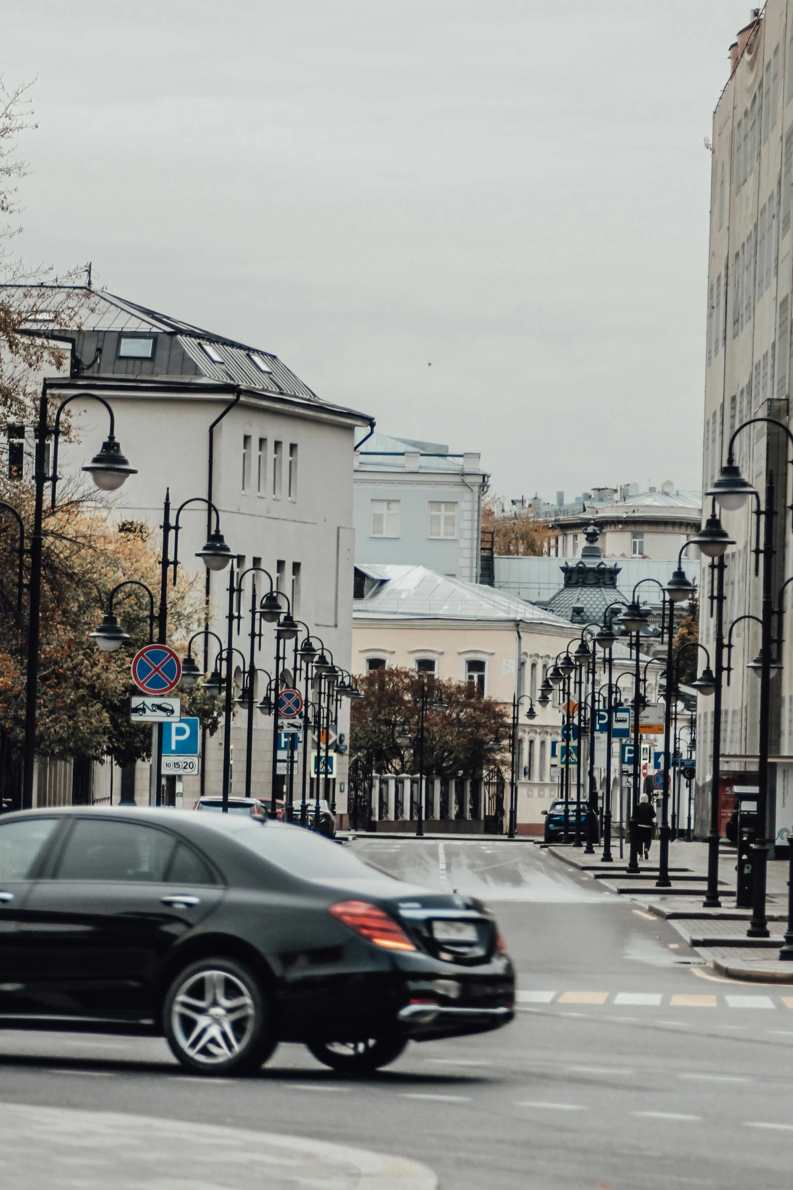 a black car driving down a street next to tall buildings, by Emma Andijewska, pexels contest winner, russian neoclassicism, northern finland, city panorama, square