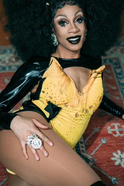 a woman with an afro sitting on a rug, featured on reddit, kitsch movement, wearing black latex outfit, with yellow cloths, jeweled costume, high angle close up shot