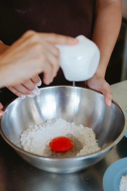 a person mixing ingredients in a bowl on a table, order, no cropping, foam, helpful