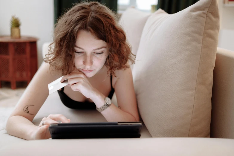 a woman laying on a couch using a tablet computer, pexels, happening, at checkout, thumbnail, digital image, student