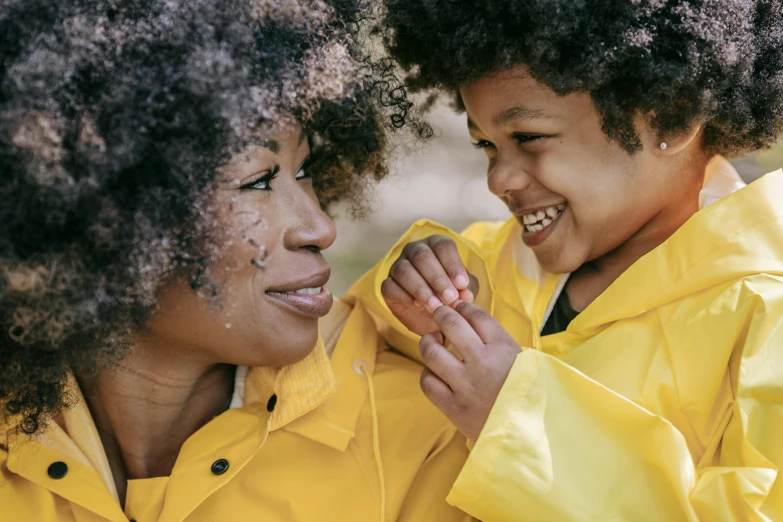 a woman standing next to a child in a yellow raincoat, pexels, with afro, pleasing, smooth details, avatar image