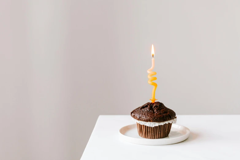 a cupcake with a lit candle on top of it, unsplash, minimalism, background image, focus on full - body, profile image, birthday