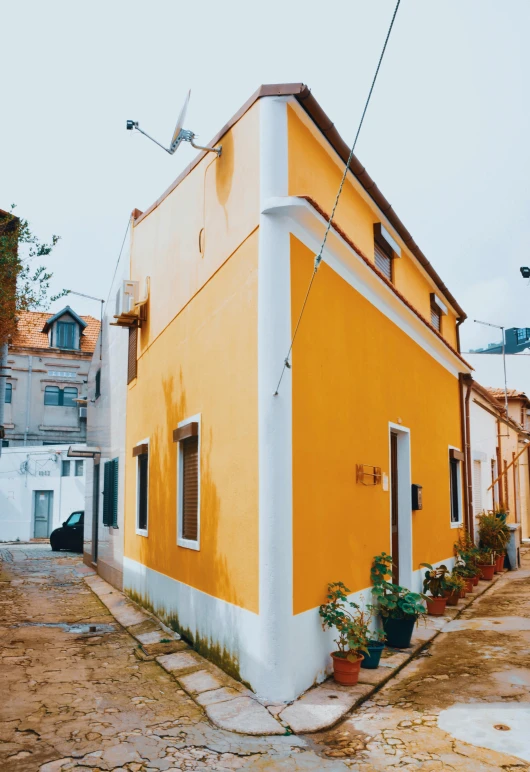 a yellow building sitting on the side of a road, inspired by Carlo Maderna, pexels contest winner, renaissance, white and orange, village house, colorized photograph, white wall complex