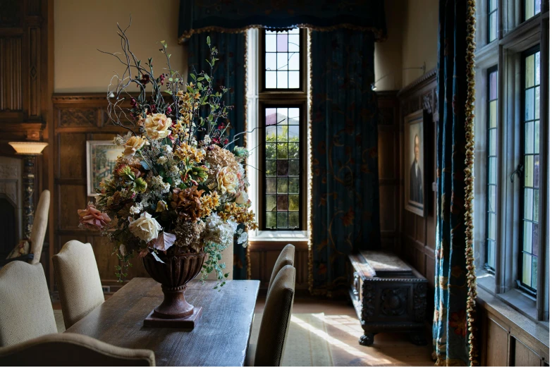 a vase of flowers sitting on top of a wooden table, inspired by Frederick Goodall, unsplash, arts and crafts movement, gothic mansion room, large windows, rich drapery, inside a castle