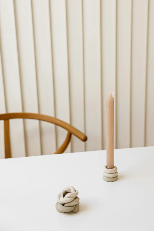 a couple of candles sitting on top of a white table, a still life, unsplash, minimalism, pale beige sky, spiral, hammershøi, dining table