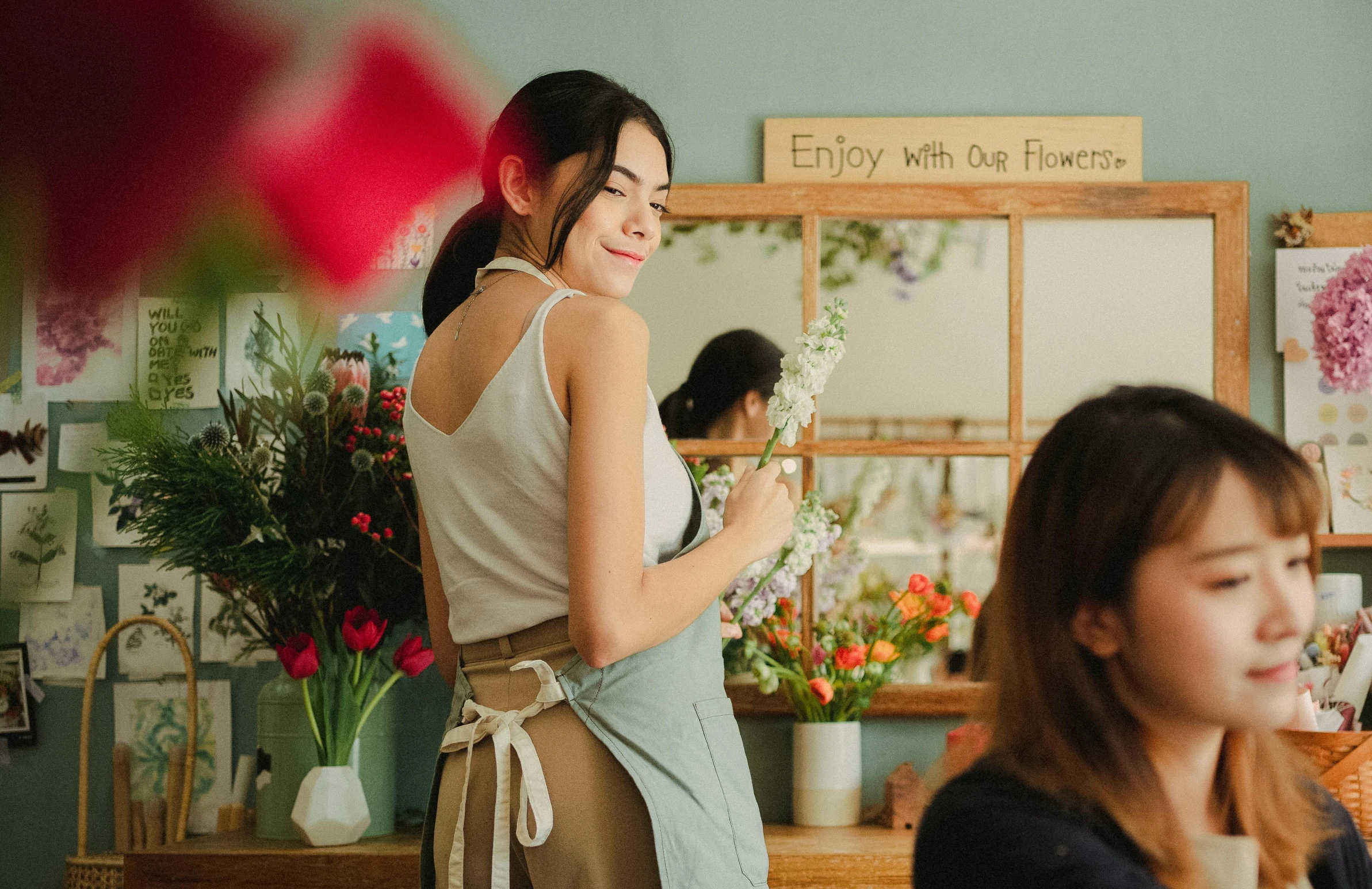 a woman standing in front of a flower shop, pexels contest winner, art nouveau, white apron, standing in front of a mirror, a young asian woman, wearing overalls