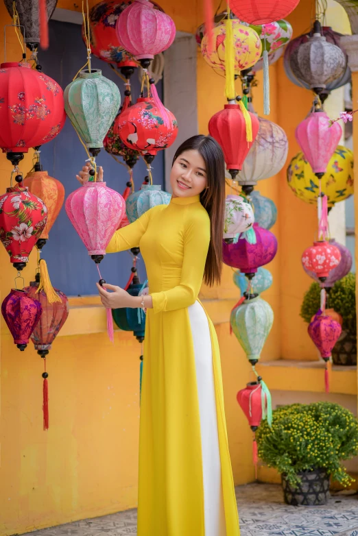 a woman in a yellow dress standing in front of a building, a picture, inspired by Tan Ting-pho, pexels contest winner, colorful lanterns, square, phong shaded, 8 k )