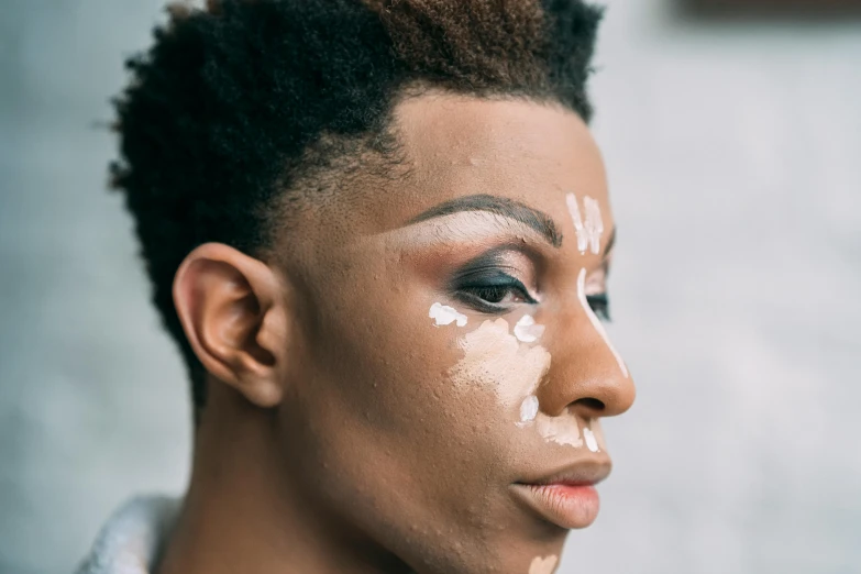 a woman with white paint on her face, inspired by Mac Conner, trending on pexels, afrofuturism, masculine jawline, putting makeup on, boy with neutral face, androgynous male