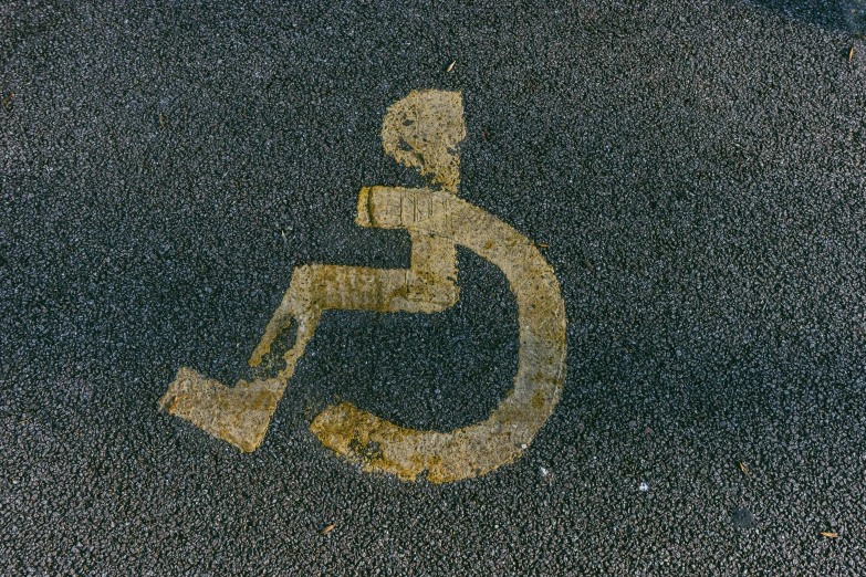 a handicap sign painted on the side of a road, by Kurt Roesch, unsplash, graffiti, square, splash image, 70s photo, gold