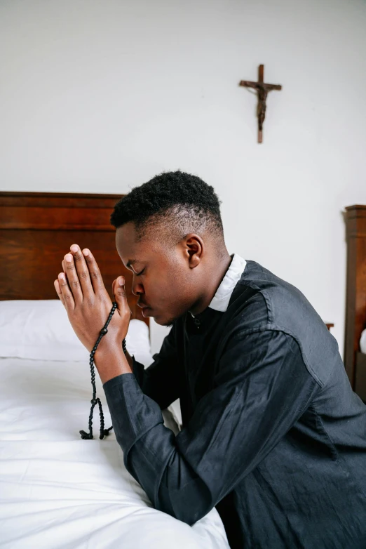 a man kneeling on a bed praying, by Francis Helps, trending on unsplash, black teenage boy, horns under his cheek, profile picture, professional image