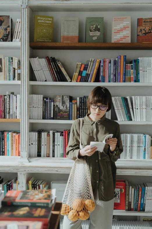 a woman standing in front of a bookshelf holding a bag, pexels contest winner, reading glasses, informative texts, gif, lulu chen