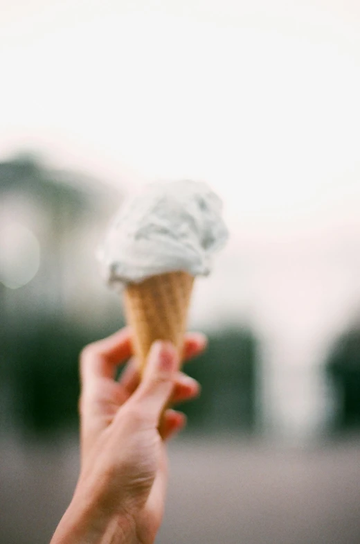 a person holding an ice cream cone in their hand, unsplash, tilt shift”, fuji superia, grey, a green