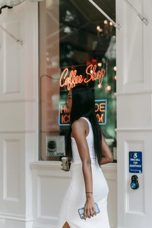 a woman in a white dress standing in front of a coffee shop, trending on unsplash, happening, dark brown skin, bright signage, outfit photo, back pose