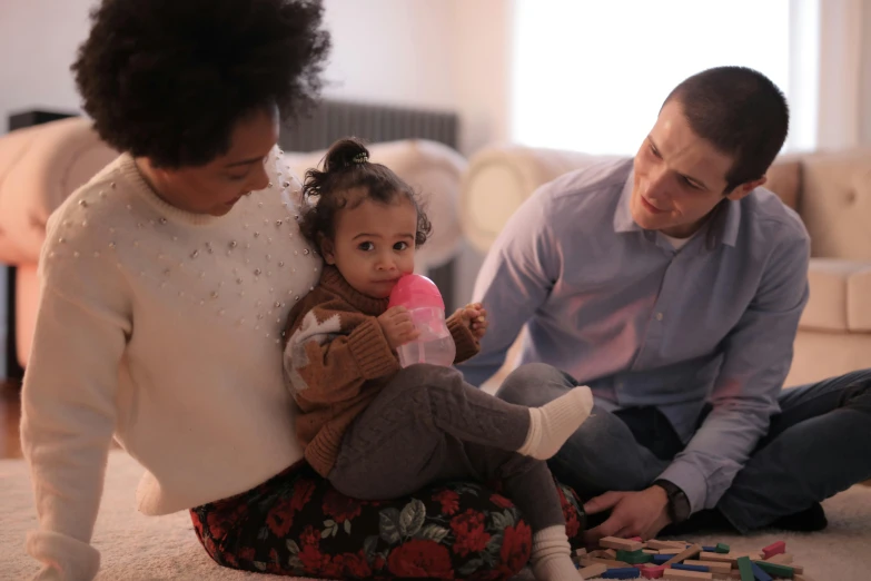 a man and woman sitting on the floor playing with a child, pexels contest winner, mixed race, promotional image, manuka, 1 5 0 4