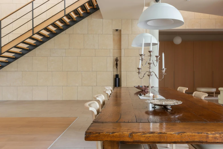 a dining room with a wooden table and white chairs, inspired by Constantin Hansen, unsplash, light and space, wide grand staircase, ancient stone tiling, sustainable materials, dim ambient lighting