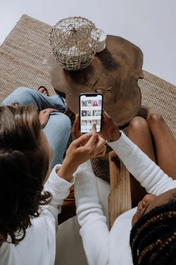 a couple of women sitting on top of a wooden table, a picture, trending on pexels, happening, mobile learning app prototype, placed in a living room, phone photo, curated collections