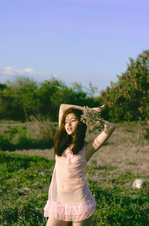 a woman standing on top of a lush green field, an album cover, inspired by Ren Hang, unsplash, aestheticism, gorgeous young korean woman, holding magic flowers, greeting hand on head, ulzzang