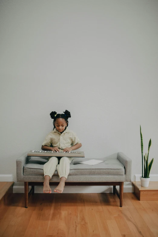 a little girl sitting on a couch reading a book, an album cover, pexels contest winner, conceptual art, keyboardist, african american, synthesizers, minimalist photo