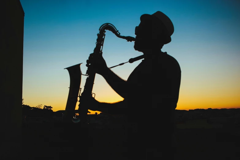 a silhouette of a man playing a saxophone, an album cover, by Carey Morris, pexels contest winner, sydney park, late summer evening, profile image, avatar image