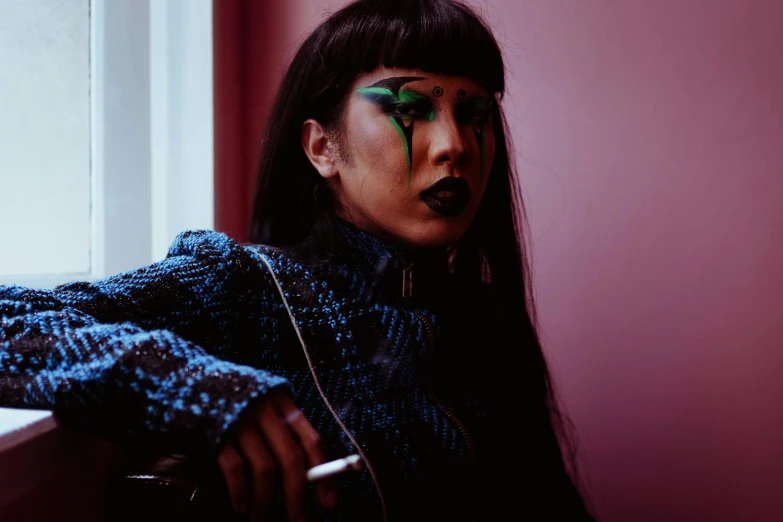 a woman with green paint on her face sitting in front of a window, an album cover, trending on pexels, graffiti, asian female, dressed as an oracle, lily frank, wearing spikes and piercings