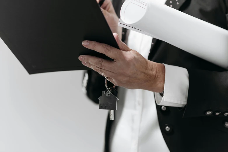 a man in a suit holding a folder and a house key, pexels contest winner, private press, white suit and black tie, developers, a man wearing a black jacket, close up shot from the side