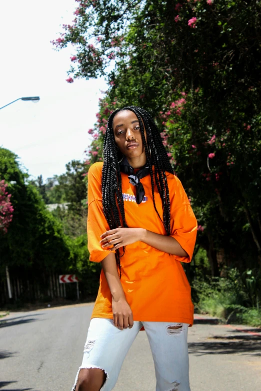 a woman riding a skateboard down a street, an album cover, featured on reddit, wearing an orange t-shirt, box braids, los angeles ca, portrait mode photo